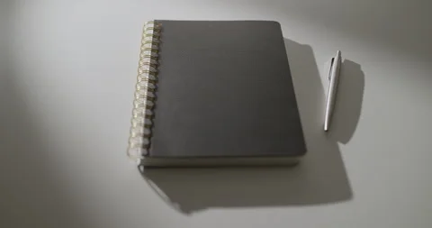 Orbit Around Black Notebook and Pen on White Table in Dramatic Light Stock Footage 346695305