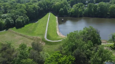 Orbit drone shot over a walking path along a calm lake Stock Footage 341272454