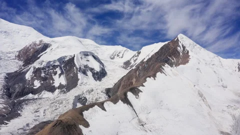 Orbit flying drone 4K video of glacier and Lenin peak wall under clear sky with Stock Footage 314084860