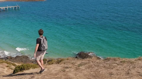 Orbit following a young man with backpack hiking down a hill revealing pristine  Stock-Footage 104582963