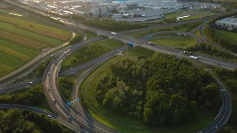 Orbit over a highway interchange rising to reveal an automobile plant at sunset 스톡 동영상 344766817