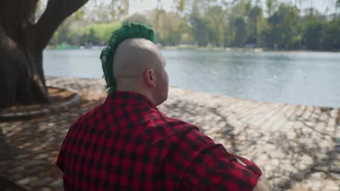 Orbit shot from behind of a man playing guitar in front of a lake Stock-Footage 139274356