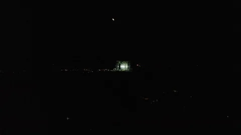 Orbit shot of Byron Bay lighthouse on at night with moon in background Stock Footage 128956903