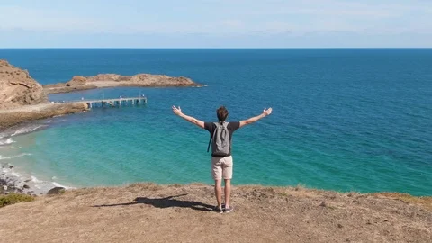 Orbit of a young man with backpack celebrating his ascent to the top of a hill i Stock Footage 104582944