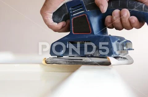 Orbital sander in use, sanding old door for a new lick of paint. Stock Photos