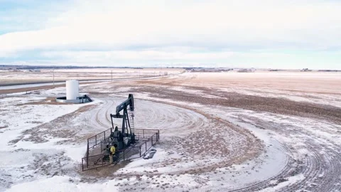 Orbiting an active oil pumpjack that is producing with an aerial view. Stock Footage 233614826