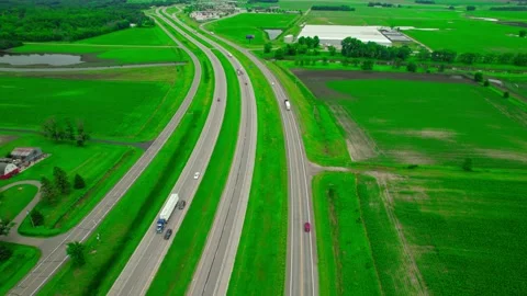 Orbiting aerial of Interstate 94 cutting through vibrant green farmlands Stock Footage 287199626