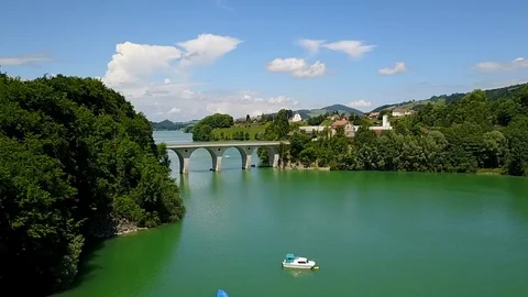 Orbiting around beautiful bridge on idyllic blue lake - aerial shot Stock Footage 128748895
