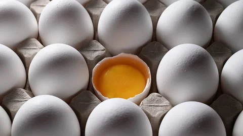 Orbiting camera reveals a fresh, golden yolk in a half-opened egg carton. Stock Footage 318850722