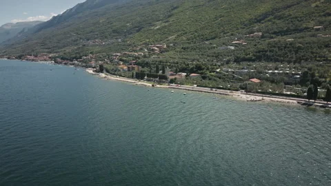 Orbiting drone aerial over mountain lake shoreline and village 4K 스톡 동영상 330991839