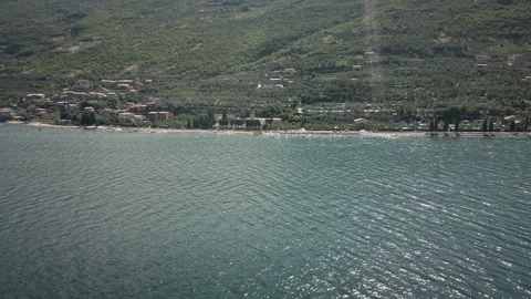 Orbiting drone aerial over mountain lake shoreline and village 4K in the Vídeo Stock 331028319