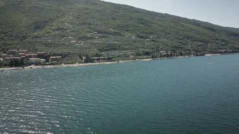 Orbiting drone flies over mountain lake shoreline and village 4K 스톡 동영상 330991805