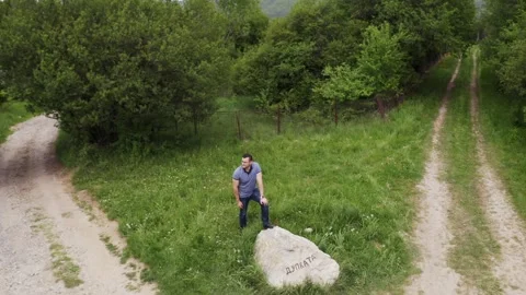 Orbiting drone shot of a tourist standing on a rock, a natural landmark Stock Footage 264798640