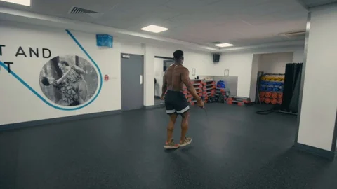Orbiting shot of fit man using a skipping rope in the gym Stock Footage 89577501