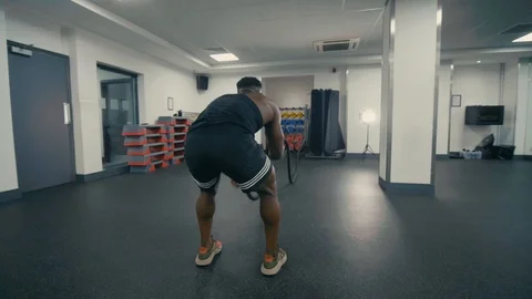 Orbiting shot of muscular man using heavy ropes in a gym setting Video stock 89577463