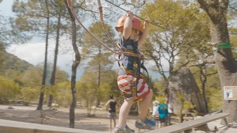 Orbiting smooth shot of toddler on rope bridge adventure park corsica Stock Footage 88903701