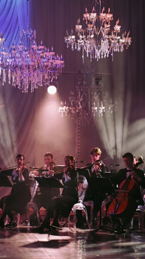 The orchestra on stage performs under luxurious chandeliers, the soft lighting Stock Footage 306338416