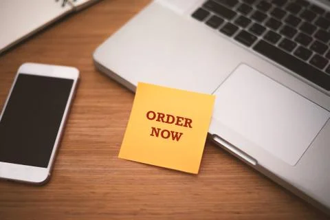 "Order Now" text on post it paper near laptop and smart phone on wood table,  Stock Photos