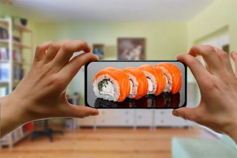 Order sushi set via the mobile app on your smartphone from home. Stock Photos