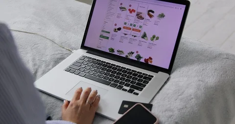 Ordering food online using website on laptop. Woman sitting on sofa Видео 127493718