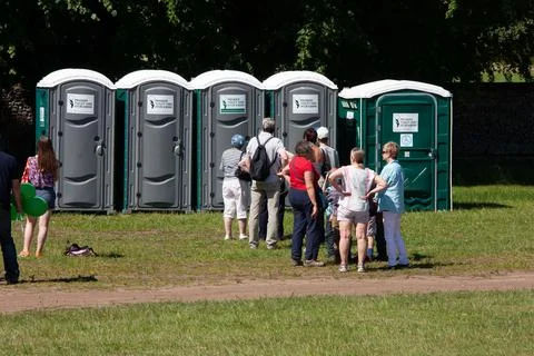 Orderly queue of people waiting to use temporary toilets at the country show 스톡 사진