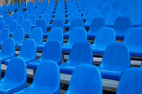 Orderly rows of empty blue seats in a grandstand. Photos