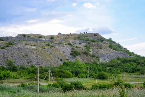 Ore slag dumps after processing. Old stepped terricon in form of a hill with  Stock Photos