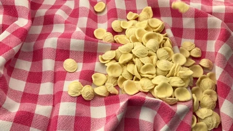 Orecchiette pasta fall on red checkered tablecloth Stock Footage 187163998