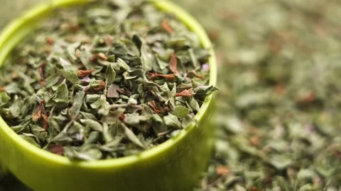 Oregano flakes falling in green plastic jar lid Stock Footage 337941759