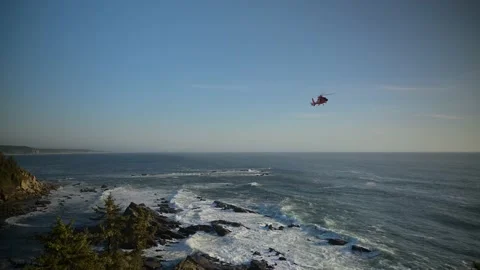 OREGON - 5.9.2025 - A US Coast Guard helicopter hovers over the rocky shore of Vídeo Stock 312863652