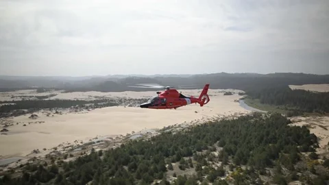 OREGON - 5.9.2025 - A US Coast Guard helicopter flies over a sandy region of Stock-Footage 312863707
