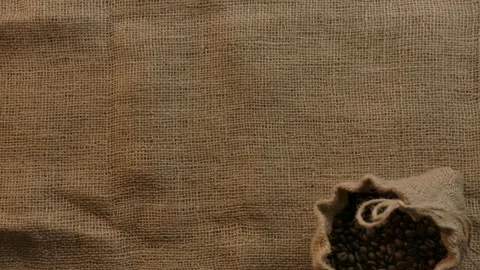 Organic authentic jute bag with roasted coffee beans falling in slow motion on Stock Footage 135376240