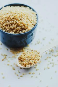 Organic bulgur raw wheat grain in ceramic bowl Stock Photos