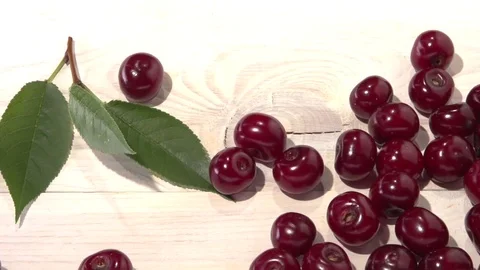 Organic cherries fall and roll against a white background wooden table. Video stock 78023703