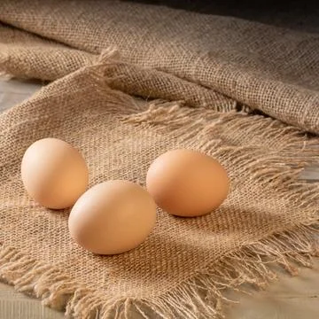 Organic chicken eggs displayed on rustic table with burlap covering Foto stock