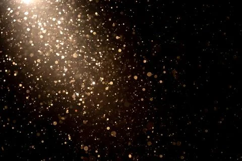 Organic dust particles floating in light ray on black background. Glittering Stock Photos