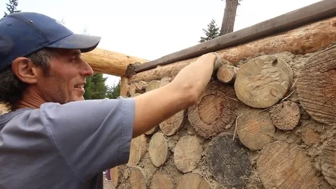 Organic farmer making natural wall with logs and cob mud. Stock Footage 80392215