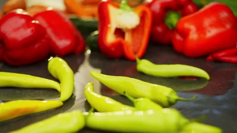 Organic green hot pepper falling on the table forming splashes of water Stock Footage 296362083