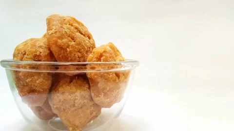 Organic Jaggery or Gur pieces in a glass bowl rotating against a clean white Stock Footage 284106912