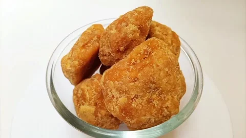 Organic Jaggery or Gur pieces in a glass bowl rotating against a clean white Stock Footage 284106916