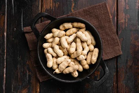 Organic peanuts in shell, on old dark wooden table background, top view flat  Stock Photos