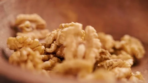 Organic peeled walnut kernels falling into a rustic wooden dish close up Stock Footage 248381064