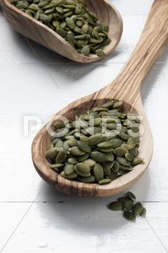 Organic Pumpkin Seeds On Wooden Spoons