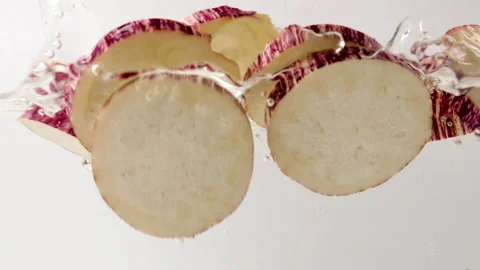 Organic sliced red eggplants falling and splashing into fresh water Stock Footage 171180087