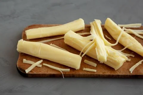 Organic String Cheese on a rustic wooden board on a gray background, side vie Stock Photos