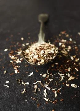 Organic tea blend on a rustic spoon, dark stone background Stock Photos