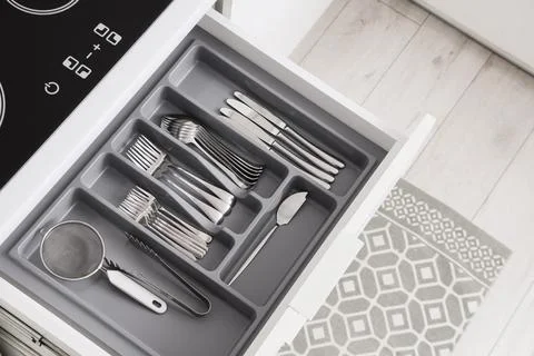 Organized kitchen drawer with silverware and utensils in a gray cutlery tray  Stock Photos