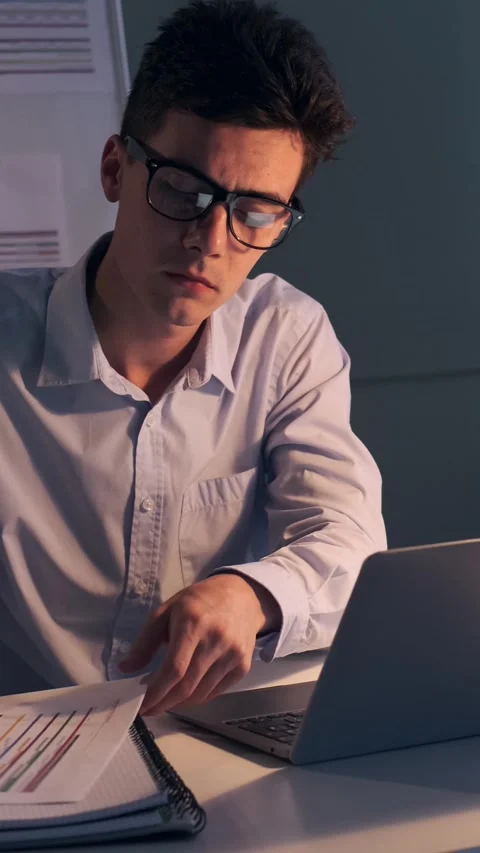 Organized Office Worker Engaged In Paperwork Using Laptop In The Night Office Video stock 289758766