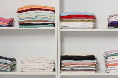 Organized stacks of folded clothes in a white closet, Home organization and d Stock Photos