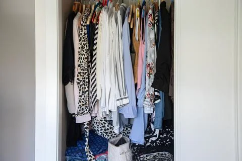 Organized wardrobe with patterned shirts and jackets on hangers, bedroom closet Stock Photos